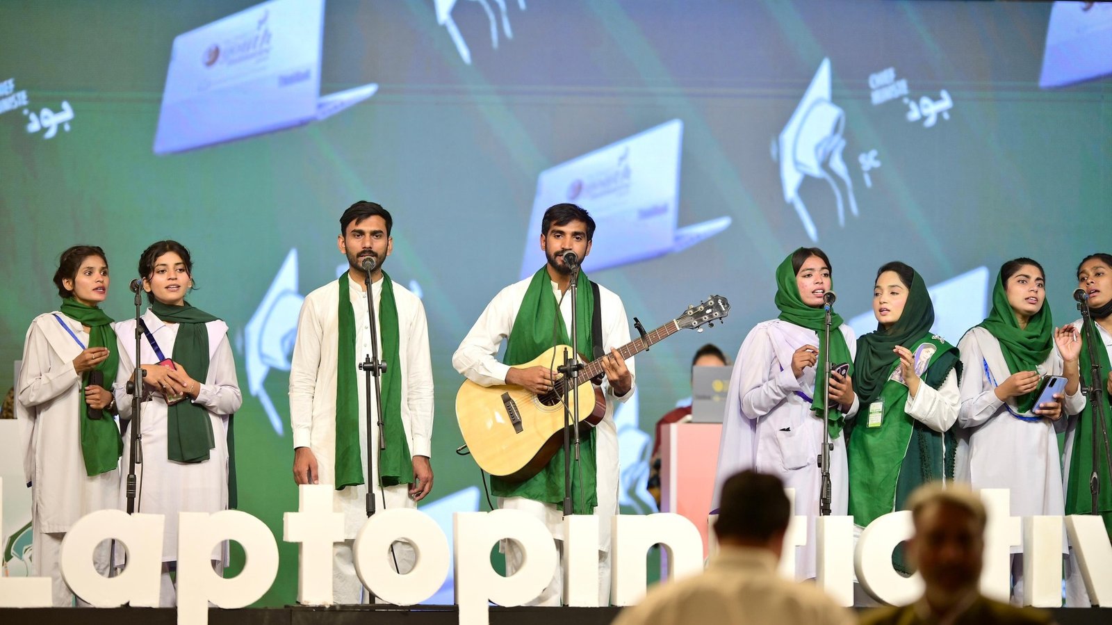Students performing on stage during a laptop distribution ceremony
